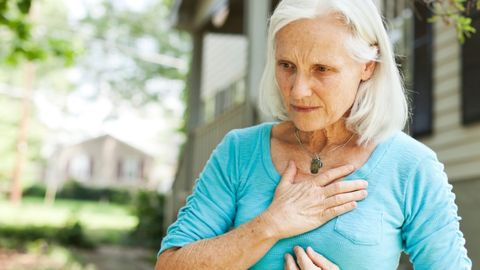 A woman is experiencing heartburn and is thinking to call the heartburn center to learn about heartburn treatment options.